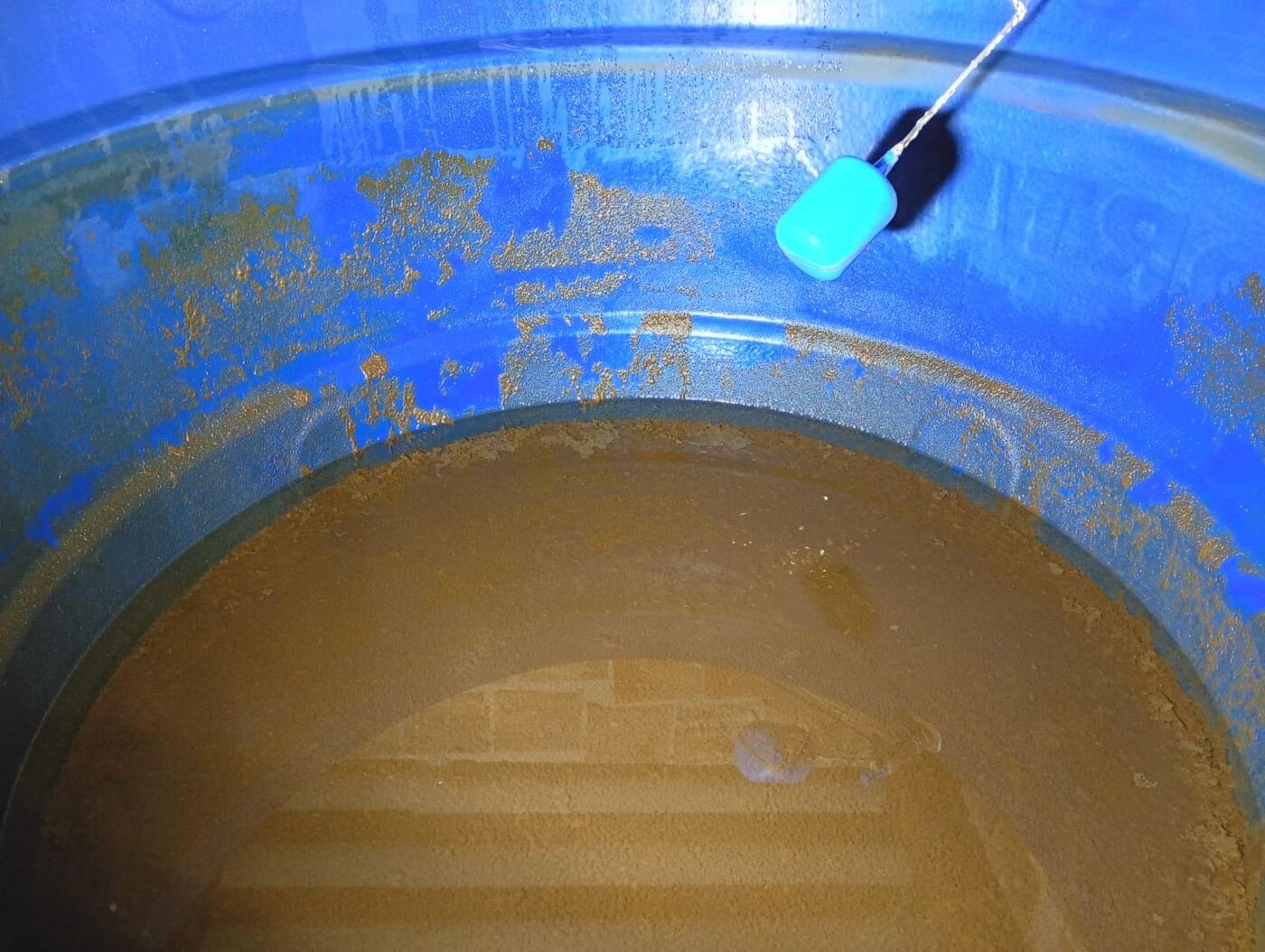 Caixa d'água suja, com lodo e sedimento no fundo, antes da limpeza