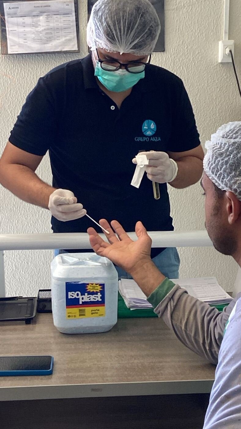 Técnico realizando swab na mão de colaborador